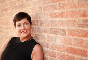 stephanie low standing against a brick wall