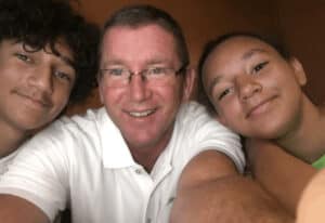 Tony Woodall con una camisa blanca tomando un selfie con dos jóvenes