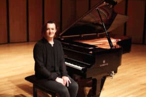 Lucas Smith seated at piano dressed in black