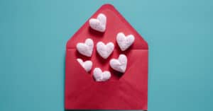 White hearts coming out of a red envelope in front of a light green background