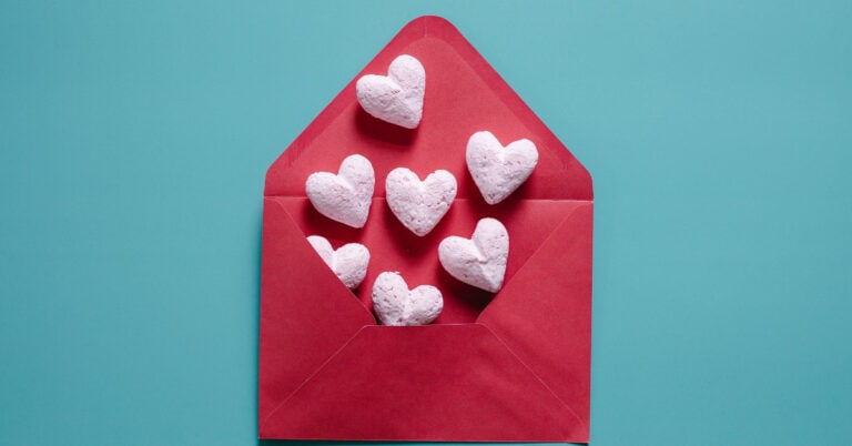 White hearts coming out of a red envelope in front of a light green background