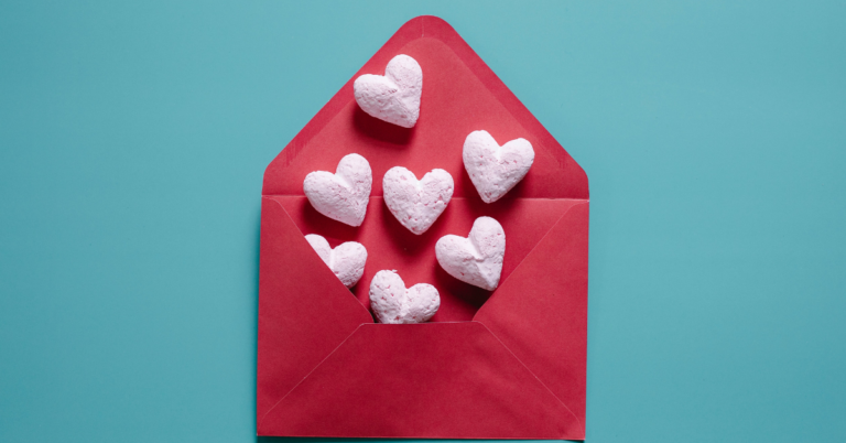 White hearts coming out of a red envelope in front of a light green background