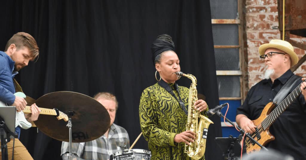 Hope plays saxophone with band Gritty City Bang Bang outside on stage.