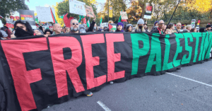 People hold red, black, white, and green banner in pro-Palestine march.