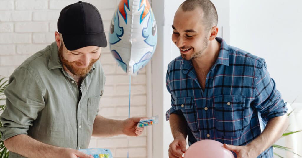 Gay men smiling as they decorate. 7 Ways to Beat the Winter Blahs, via Pexel