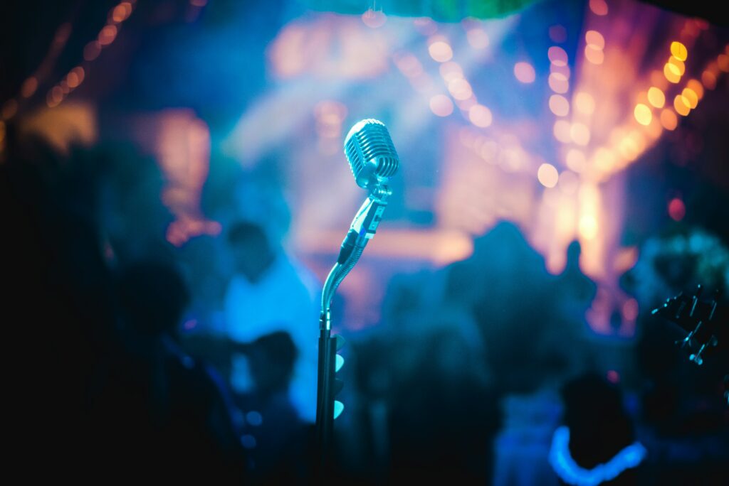 A microphone in front of a crowd on karaoke night via Pexel