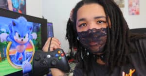 Lo Norman holding a controller in front of Sonic The Hedgehog game on a mid-sized screen