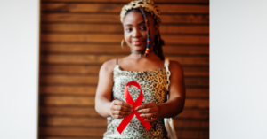 Concientización sobre el VIH/SIDA. Mujer negra sostiene cinta de concientización sobre el sida. Imagen vía Canva