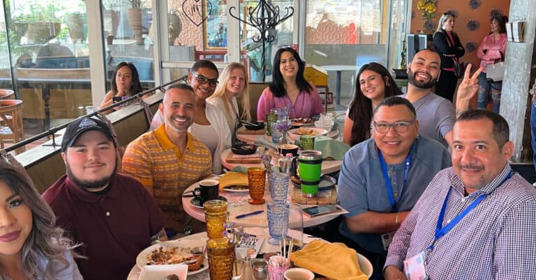 National Latinx HIV Conference: Journey of Renewal. Image of Latin people surrounding a table covered with food