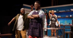 Three gay black men on stage in clothes like they might be about to cook in The Hot Wing King production
