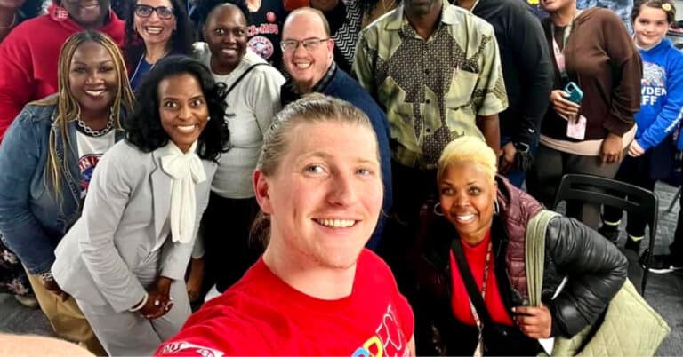 Noah Nordstrom smiling in red with local community members