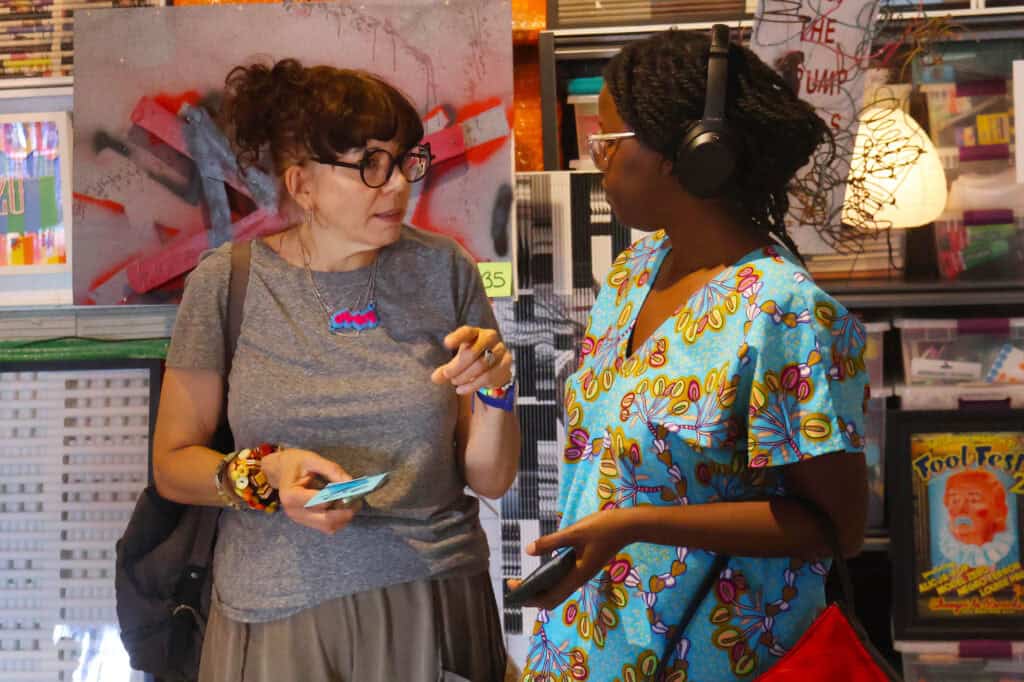 Two women in conversation inside a bookstore, one holding a snack and phone. — focuslgbt.com