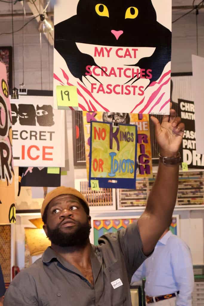 Person holding a protest sign with a black cat and pink text. — focuslgbt.com