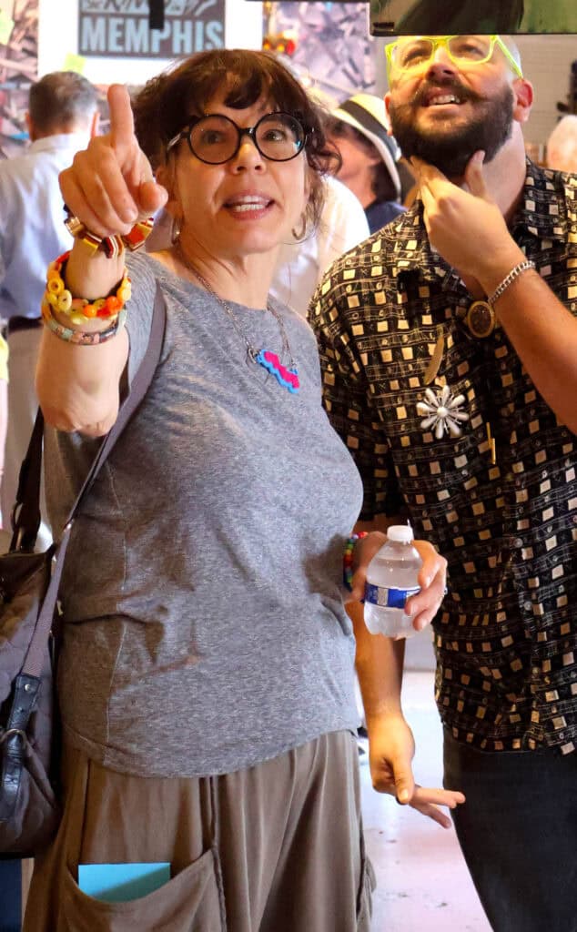 Woman with glasses and colorful bracelets points at the camera at Pride event. — focuslgbt.com