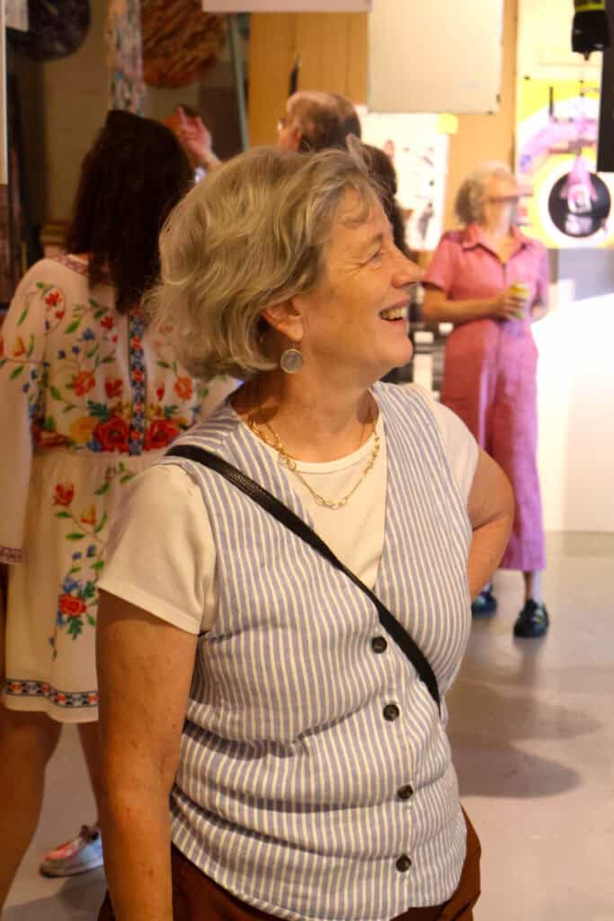 Older woman with gray hair smiling at an indoor event. — focuslgbt.com