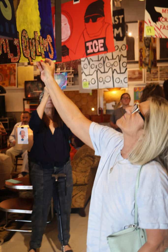 Woman with glasses reaches for a colorful sign at an indoor event. — focuslgbt.com