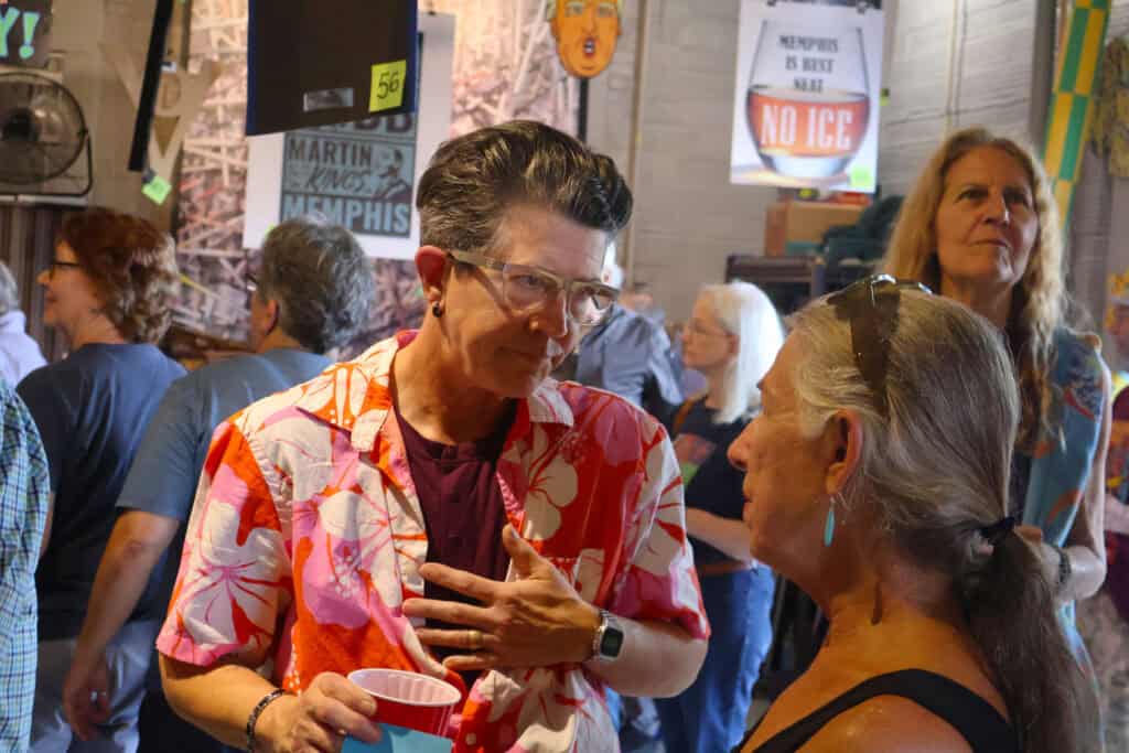 Two women engage in conversation at a crowded indoor event. — focuslgbt.com