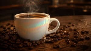 A white ceramic espresso cup filled with coffee on a wooden table with coffee beans scattered. — focuslgbt.com