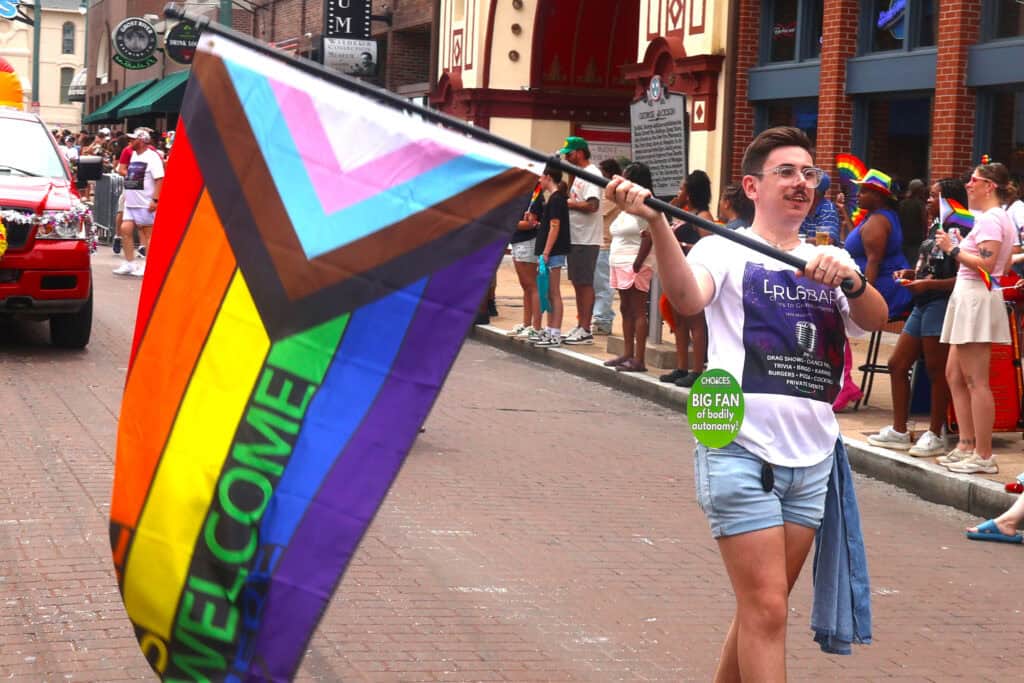Person holding a rainbow pride flag at Memphis Pride parade, 2023. — focuslgbt.com