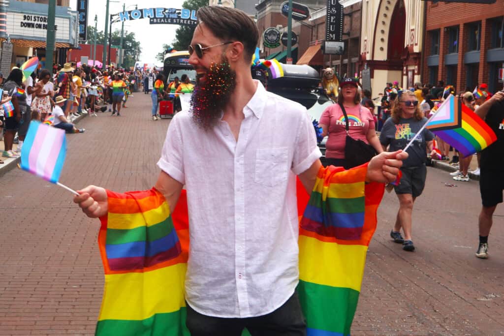 Person with rainbow flag draped over shoulders at Pride parade in Memphis. — focuslgbt.com