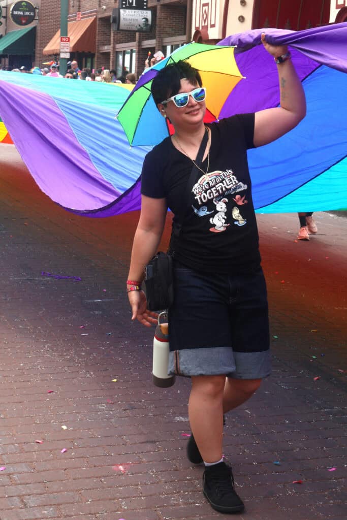 Person holding rainbow flag and umbrella at Pride parade in Memphis. — focuslgbt.com