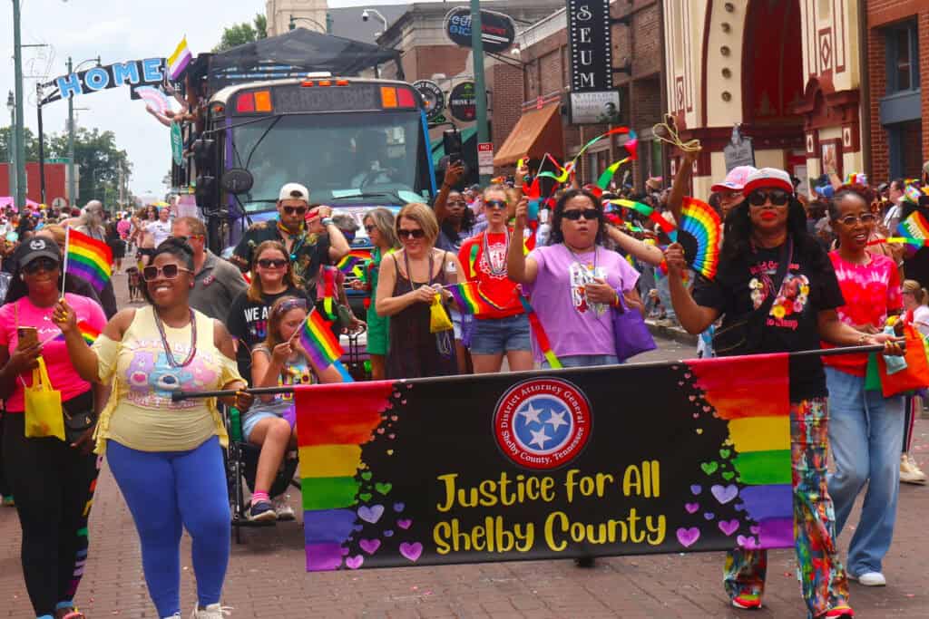Participants in rainbow attire hold a Justice for All Shelby County banner at Pride parade. — focuslgbt.com