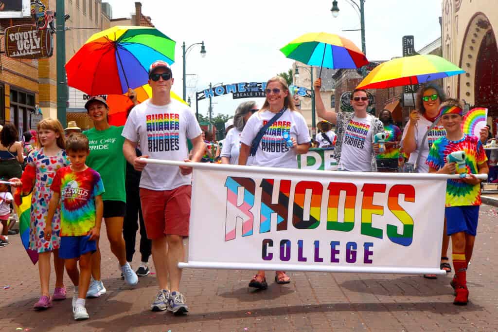 Participants in rainbow shirts hold a Rhodes College banner during Pride parade. — focuslgbt.com