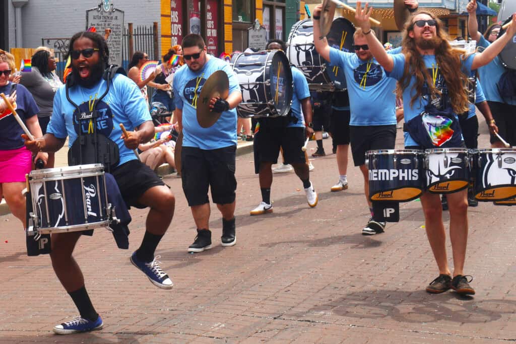 Performers in blue shirts play drums during Memphis Pride parade, June 2023. — focuslgbt.com