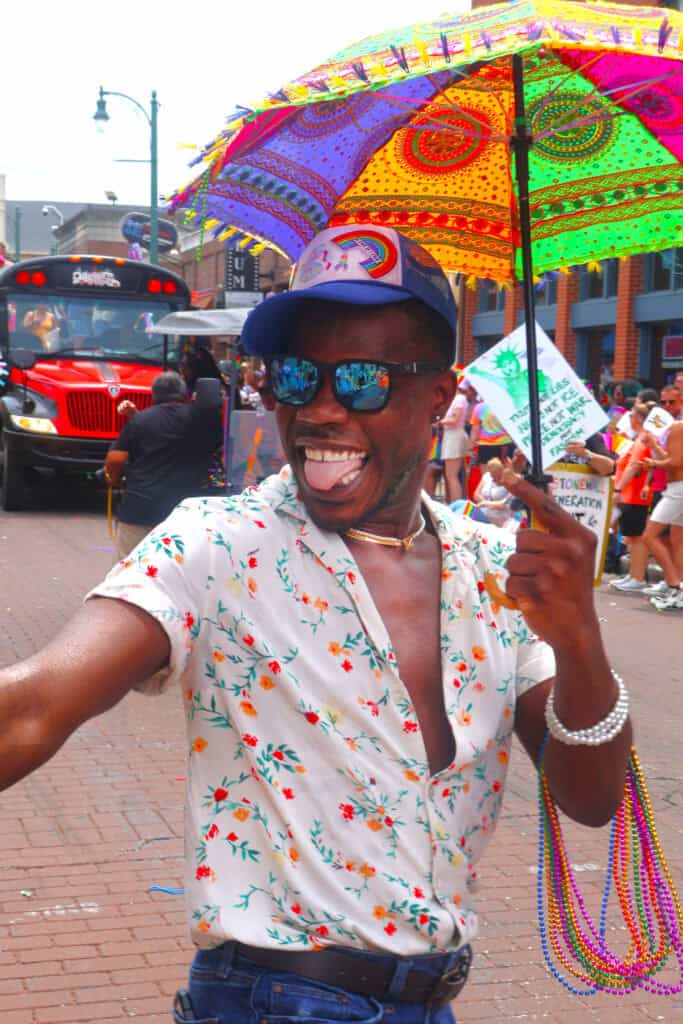 Person smiling with rainbow umbrella at Pride parade in Memphis, July 2023. — focuslgbt.com