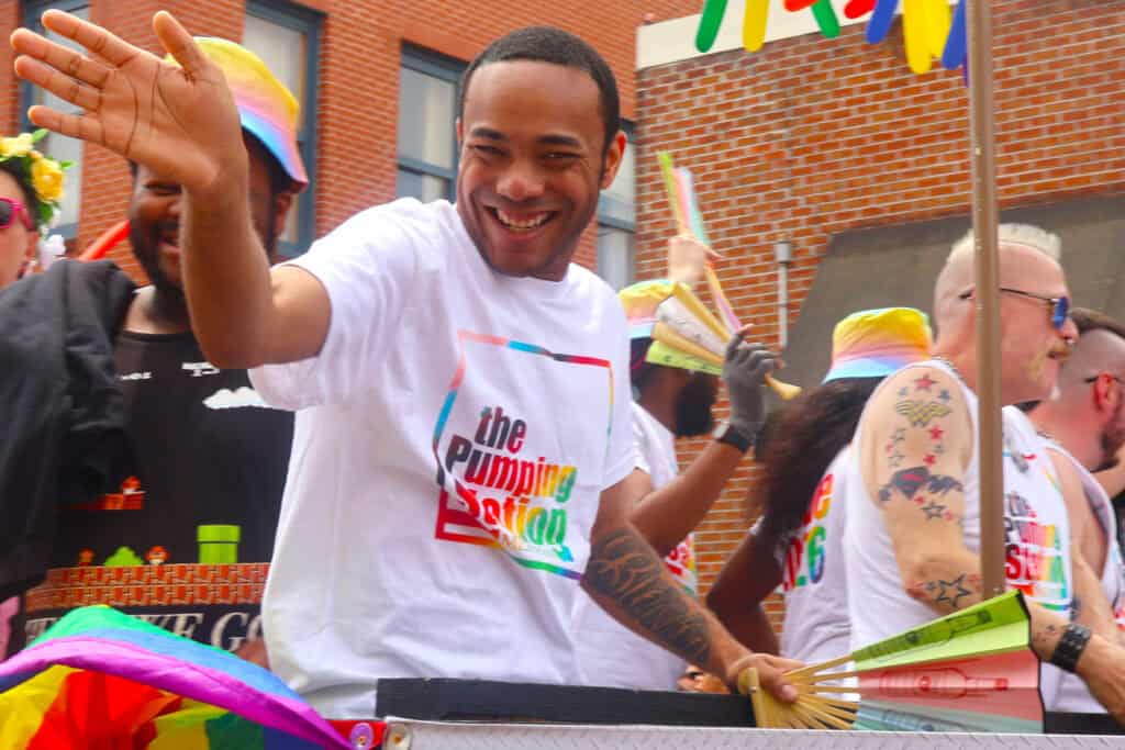 Performer in a white T-shirt waves at parade spectators during Memphis Pride Festival. — focuslgbt.com