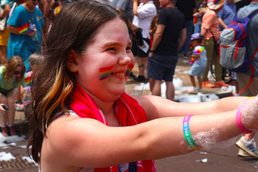 Girl with rainbow face paint and red scarf at Pride festival in Memphis. — focuslgbt.com