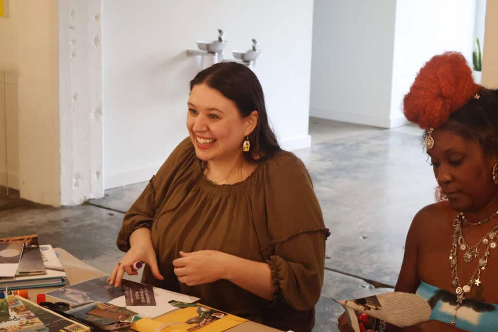 Two women sit at a table with colorful books and papers, smiling and engaging in conversation. — focuslgbt.com
