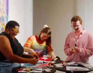 Three people working on colorful craft projects at a table. — focuslgbt.com