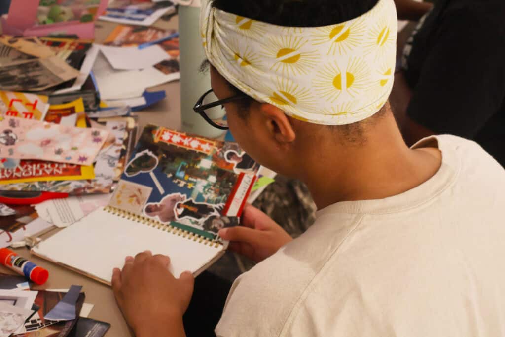 Person with glasses and a yellow and white headband looks at a scrapbook. — focuslgbt.com