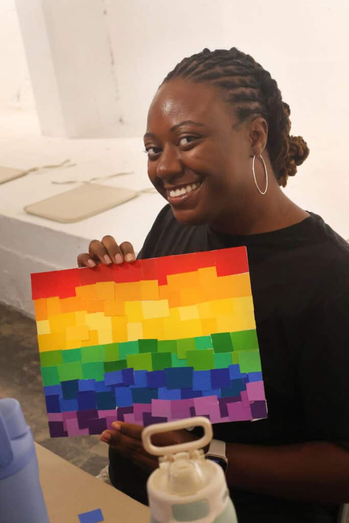 Person holding a rainbow pixel art painting at an indoor event. — focuslgbt.com