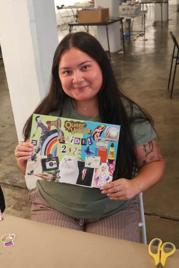 Young woman holding a colorful collage at an indoor event. — focuslgbt.com