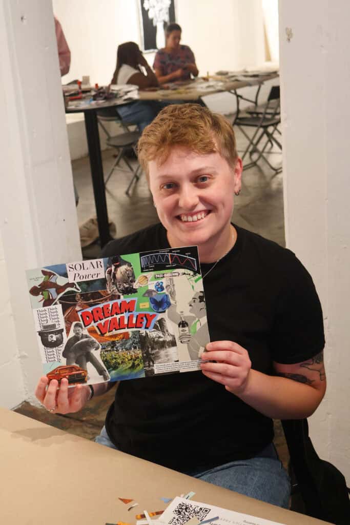 Person with short red hair holding a colorful magazine at a table. — focuslgbt.com